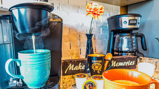 Cozy coffee setup with mugs and a flower on a windowsill.