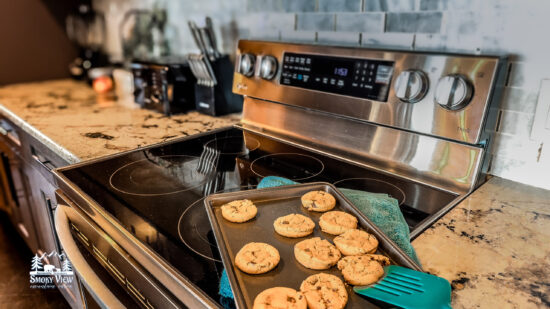 Freshly baked chocolate chip cookies cooling on a stove.