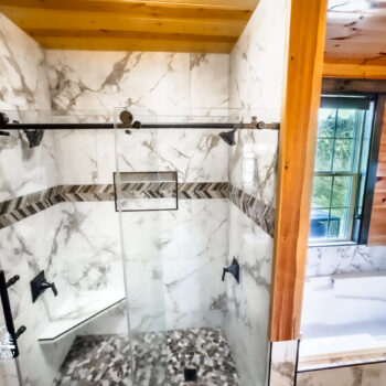 Modern shower with marble tiles and pebble floor.