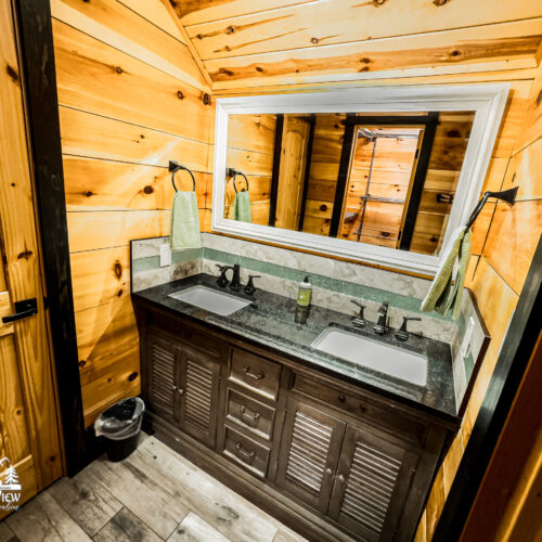 Rustic bathroom with wooden walls and a modern double sink vanity.