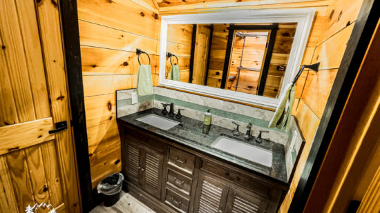 Rustic bathroom with wooden walls and a modern double sink vanity.