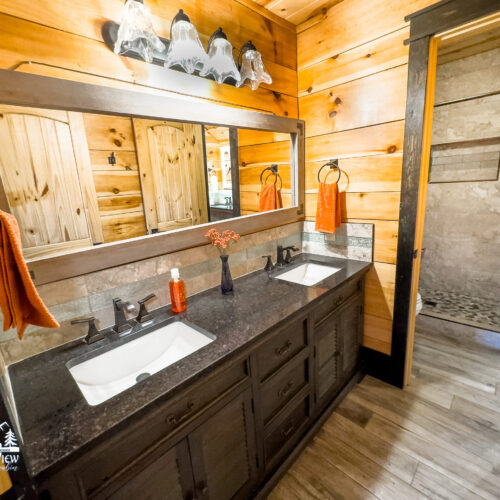 Rustic bathroom with wooden walls and double sink vanity.