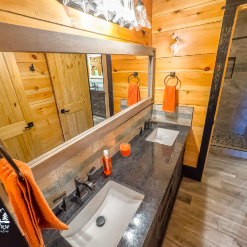 Rustic wooden bathroom with modern sinks and orange accents.