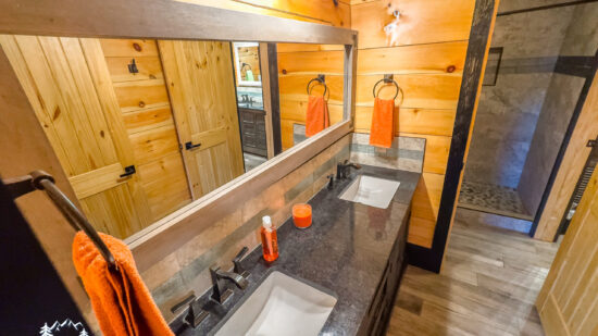Rustic wooden bathroom with modern sinks and orange accents.