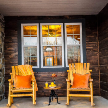 Cozy porch with two orange cushioned chairs and a small table.
