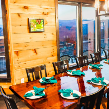 Cozy wooden dining room with sunset mountain views and neatly set table.