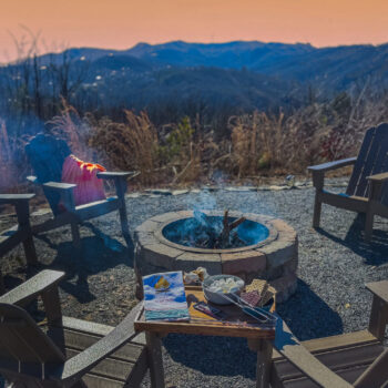 Cozy outdoor fire pit setup at sunset with chairs and snacks.