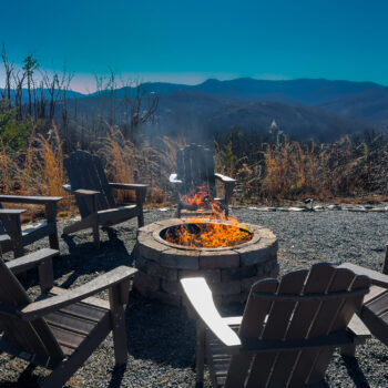 Cozy outdoor fire pit surrounded by Adirondack chairs at sunset.
