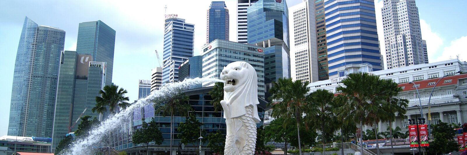 The Merlion statue spouting water with Singapore's skyline in the background.