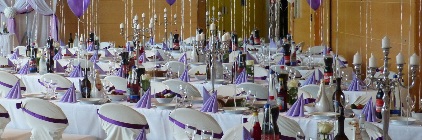 Elegant banquet hall decorated with purple and white balloons and neatly arranged tables.
